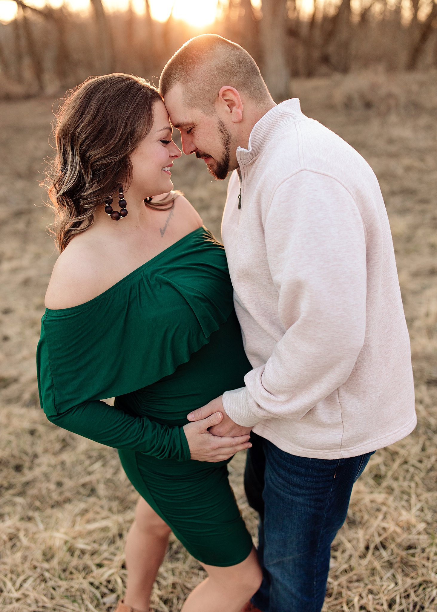 Couple posed holding each other and pregnant belly in Scott county park Iowa