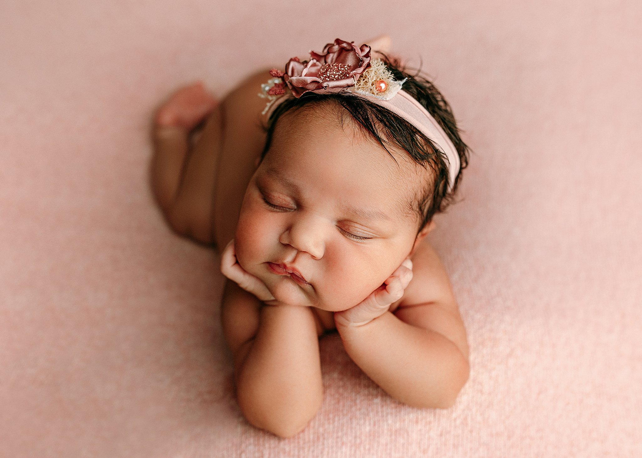 newborn baby in the froggy pose on pink fabric